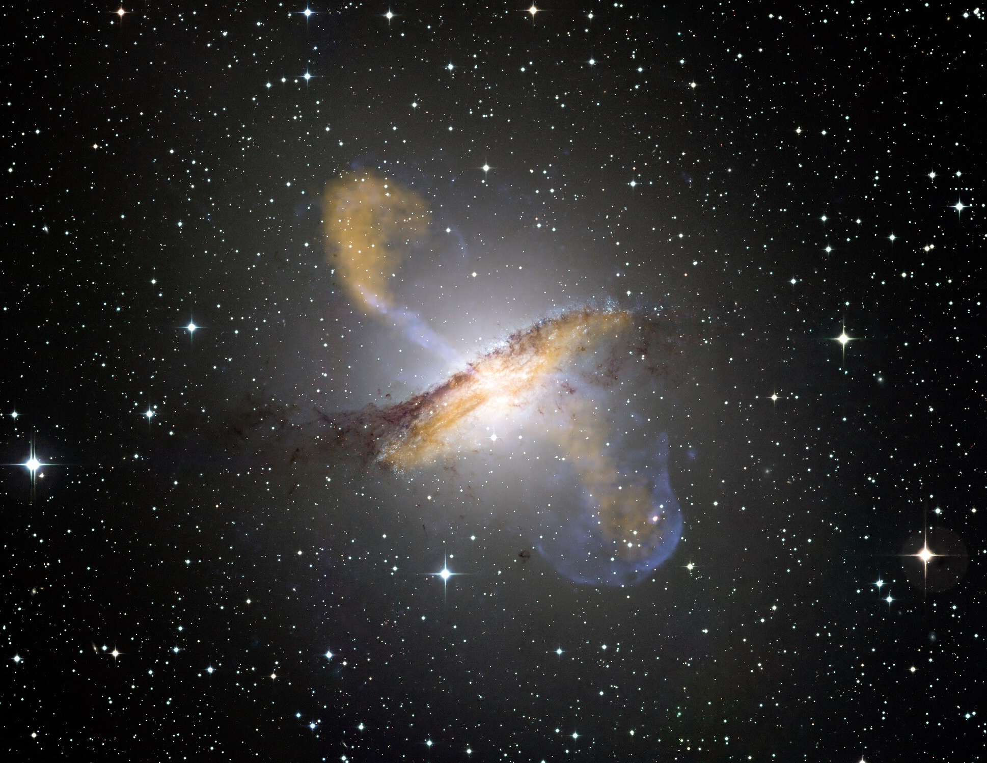 Aktivní galaxie Centaurus A s malebnými polárními výtrysky. Kredit: ESO/WFI (Optical); MPIfR/ESO/APEX/A.Weiss et al. (Submillimetre); NASA/CXC/CfA/R.Kraft et al. (X-ray).