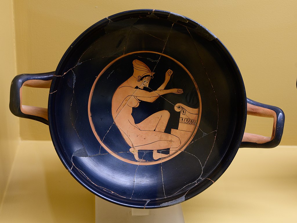 Červeno-figurový kylix od Malíře Chairias, hetéra klečí u oltáře. Kredit: Zde, Wikimedia Commons. Licence CC 4.0.